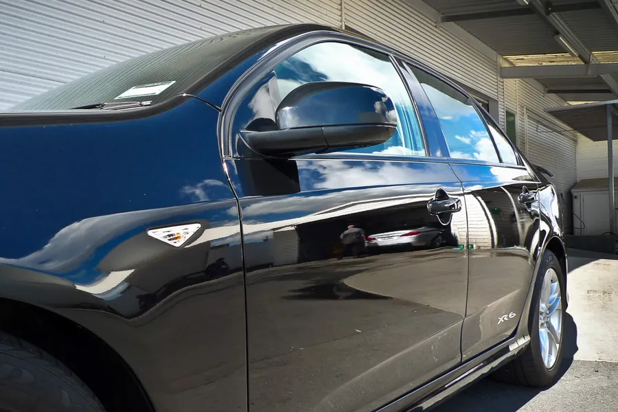 Close-up of a freshly detailed black vehicle's door panel