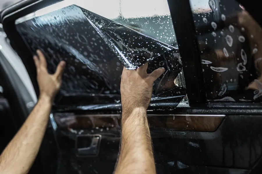 Installer applying ceramic window tint to a vehicle's rear window